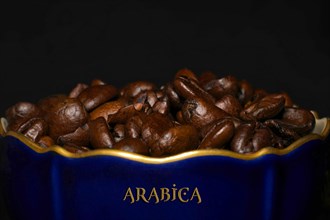Roasted Arabica coffee in a porcelain cup in cobalt blue with gold rim and the inscription Arabica