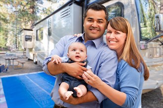 mixed-race family in front of their beautiful RV at the campground