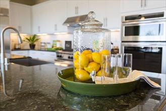 Abstract of interior kitchen counter with lemon filled pitcher and drinking glasses