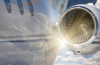 Private jet and engine abstract with sunburst and clouds