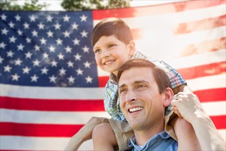 Father with son piggy back riding in front of american flag
