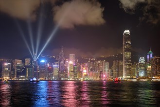 Hong Kong skyline cityscape downtown skyscrapers over Victoria Harbour in the evening illuminated with lasers with tourist boat ferries