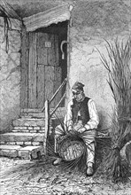Basket weaver sitting in front of his house weaving a wicker basket