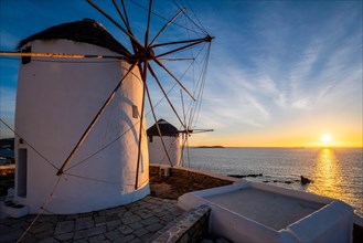 Scenic view of famous Mykonos town windmills Traditional greek windmills on Mykonos island on sunset with dramatic sky
