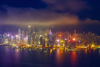 Aerial view of illuminated Hong Kong skyline cityscape downtown skyscrapers over Victoria Harbour in the evening. Hong Kong