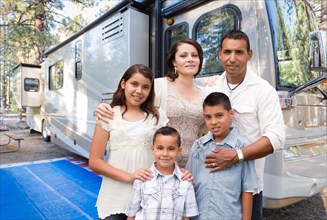 Happy hispanic family in front of their beautiful RV at the campground