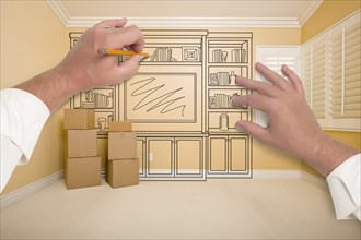 Hands drawing beautiful entertainment unit in room with moving boxes