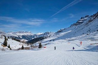 View of a ski resort piste with people skiing in Dolomites in Italy. Canazei