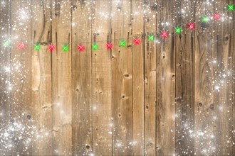 Lustrous wooden background with bright green and red christmas lights and snowy border