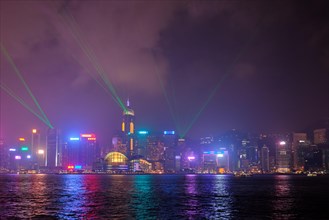 Hong Kong skyline cityscape downtown skyscrapers over Victoria Harbour in the evening illuminated with lasers with tourist boat ferries