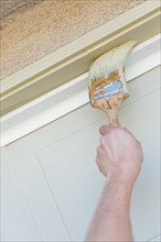 Professional painter cutting in with A brush to paint garage door frame