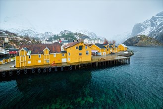 Panorama of Nusfjord authentic fishing village with yellow rorbu houses in Norwegian fjord in winter