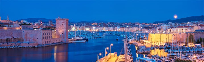 Panorama of Marseille Old Port and Fort Saint-Jean illumintaed in night with moon