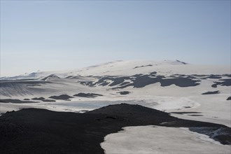 Barren hilly volcanic landscape of snow and lava sand