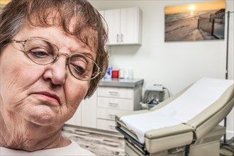 Worried senior adult woman waiting in doctor office