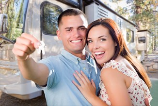 Young military couple holding keys in front of new RV