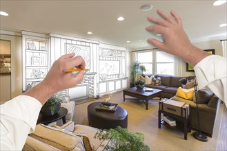 Male hands drawing entertainment center unit over photo of beautiful home interior