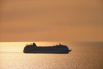 Cruise ship silhouette in Aegean sea on sunset. Mykonos island