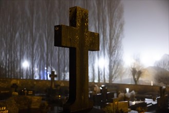 Cross in a cemetery at night with street lighting