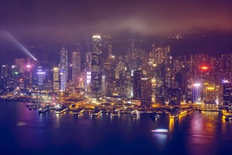Aerial view of illuminated Hong Kong skyline cityscape downtown skyscrapers over Victoria Harbour in the evening. Hong Kong