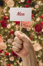 Hand holding nice card in front of decorated christmas tree