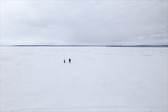 Two People stand on a wide and frozen riverscape