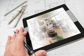 Hand of architect on computer tablet showing living room illustration photo combination over house plans