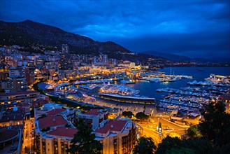 Aerial view of Monaco Monte Carlo harbour and illuminated city skyline in the evening blue hour twilight Monaco Port night view with luxurious yachts