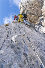 Two climbers on a via ferrata on a steep rock face