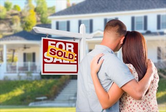 Military couple looking at house with sold for sale real estate sign in front
