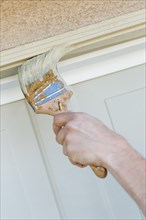Professional painter cutting in with A brush to paint garage door frame