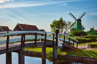 Netherlands rural lanscape with bridge over canal at windmills at famous tourist site Zaanse Schans in Holland Zaandam