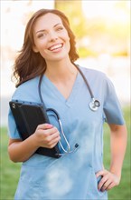 Portrait of an attractive young adult woman doctor or nurse holding touch pad outside