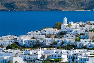 View of Plaka village with traditional Greek church and white painted houses and ocean coast. Milos island