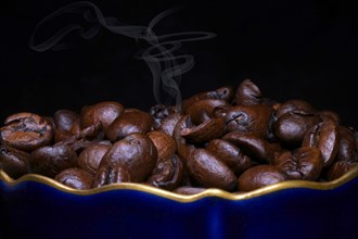 Roasted coffee of the Arabica variety in a porcelain cup in cobalt blue with gold rim