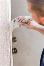 Professional painter cutting in with A brush to paint house door frame