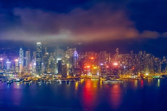 Aerial view of illuminated Hong Kong skyline cityscape downtown skyscrapers over Victoria Harbour in the evening. Hong Kong