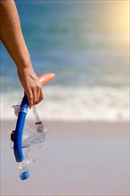 Woman holding snorkeling gear on the shoreline