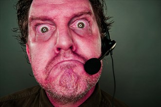 Grumpy red eyes and face frowning customer support man with headset