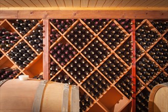 Wine barrels and bottles age inside dark cellar