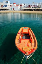 Greek fishing boat in clear sea water in port of Mykonos. Chora town