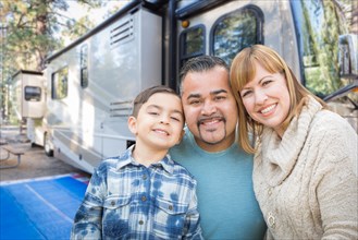 Happy young mixed-race family in front of their beautiful RV at the campground