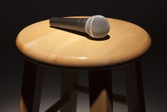 Microphone laying on wooden stool under spotlight abstract