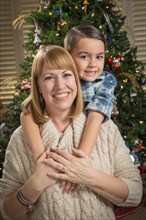 Happy mother and mixed-race son hug near their christmas tree