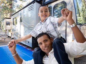 Happy hispanic father and son in front of their beautiful RV at the campground