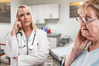 Empathetic doctor standing behind troubled senior adult woman in office