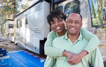 Happy african american couple in front of their beautiful RV at the campground