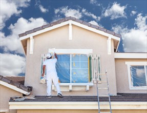 Professional house painter painting the trim and shutters of A home