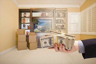 Hand holding out cash over drawing of entertainment unit in room with moving boxes