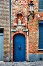 Door and window of an old house with Virgin Mary statue
